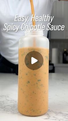 a person pouring a drink into a glass with the words easy, healthy spicy chipotie sauce