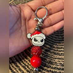 a hand holding a key chain with a skull wearing a santa hat