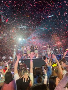 a group of people standing on top of a stage with confetti in the air