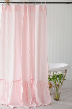 a pink shower curtain with ruffles hanging from it's side in a bathroom