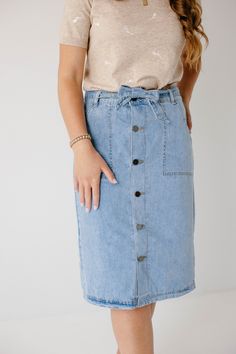 Create an instant feminine look wearing the 'Cassidy' Skirt! Featuring a button-front design and tie waist, this denim midi skirt makes a perfect choice for both casual or formal occasions. The soft, lightweight denim in a regular fit offers comfort, while the pull-on style allows easy wear. Pair the 'Cassidy' with a black tee and sneakers for a fun day in the city or running errands in town! 75% Cotton 25% Polyester Hand Wash Cold Do Not Bleach Hang to Dry Low Iron if Needed Model Height 5'7" | Casual Midi Length Denim Blue Bottoms, Casual Denim Blue Midi Bottoms, Casual Midi Length Denim Skirt With Pockets, Casual Midi Denim Skirt With Pockets, Trendy Spring Denim Midi Skirt, Trendy Midi-length Denim Skirt For Spring, Trendy Midi Denim Skirt For Spring, Trendy Spring Denim Skirt With Button Closure, Trendy Midi Length Denim Skirt