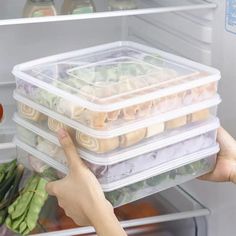 a person is reaching into an open refrigerator with food in containers on the bottom shelf