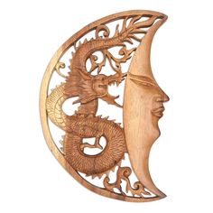 a carved wooden wall hanging with a woman's face and dragon on the moon