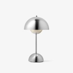 a lamp that is on top of a white tablecloth and it has a metal base