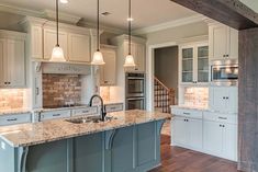 a large kitchen with white cabinets and marble counter tops