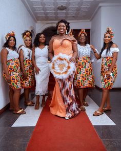 a group of women standing next to each other in front of a red carpeted floor