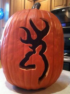 a carved pumpkin with an antelope on it's face, sitting on a kitchen counter