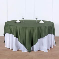 a round table with two wine glasses on it and a green cloth over the top