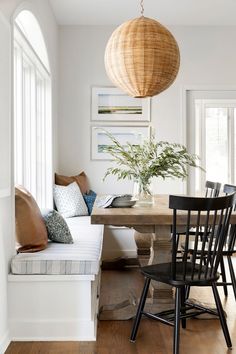 a dining room table with chairs and a bench in front of it, next to a window