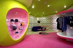 the inside of a clothing store with pink carpet and yellow shelves, shoes on display