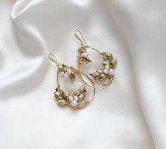 These handcrafted antique gold wedding earrings showcase a boho-inspired floral design, featuring delicate leaves and freshwater pearls. Expertly made to order, these hoop earrings add a touch of elegance and uniqueness to any bridal look. - Handcrafted in my PA studio - Genuine Austrian golden shadow crystal rock fabric leaves - Freshwater pearls - Antique gold leaves  - Available in rose gold, yellow gold or rhodium (silver) - Earrings measure 2.5 inches x 1-5/8 inch - Handcrafted in the US. - Nickel free and hypoallergenic - PLEASE ALLOW APPROX 10 BUSINESS DAYS FOR COMPLETION BEFORE SHIPPING. This is an original design by © Treasures by Agnes Browse our earrings: https://www.etsy.com/shop/treasures570?ref=seller-platform-mcnav&section_id=6861728 Browse our backdrop necklaces: https://ww Brass Filigree Hoop Earrings For Wedding, Delicate Handmade Gold Pearl Earrings, Elegant Gold Flower Earrings For Celebration, Yellow Gold Flower Earrings With Pearl Drop For Wedding, Handmade Delicate Yellow Gold Pearl Earrings, Delicate Gold Brass Hoop Earrings, Delicate Handmade Yellow Gold Pearl Earrings, Delicate Gold Hoop Earrings In Brass, Wedding Yellow Gold Flower Earrings With Pearl Drop