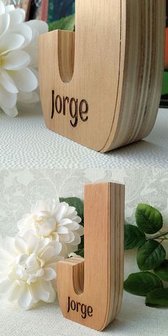 two wooden letters that are next to each other on a white tablecloth with flowers in the background