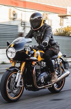 a man riding on the back of a black and yellow motorcycle