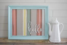 a wooden frame with the word hello painted on it next to a teapot and coffee pot