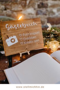 a wooden sign sitting on top of a table next to an open book and candle