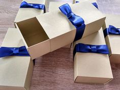 four boxes with blue bows on them sitting on a wooden table, one opened and the other closed