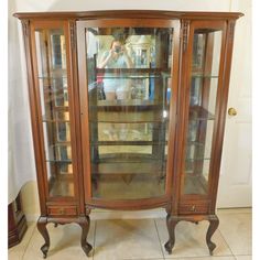 an antique china cabinet with glass doors and shelves