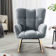 a gray chair sitting in a living room next to a window