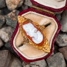 This vintage north-to-south cameo ring features a bezel set hard stone cameo with an elongated floral bezel. The ring is crafted in 14k yellow gold and has been re-shanked with 10k yellow gold. The ring also features a high carat gold wash with natural patina. Antique Oval Cameo Signet Ring, Antique Cameo Signet Ring For Weddings, Antique Cameo Signet Ring For Formal Occasions, Victorian Style Cameo Signet Ring For Formal Occasions, Vintage Cameo Signet Ring For Anniversary, Victorian Style Formal Signet Ring With Cameo, Heirloom Oval Cameo Signet Ring, Antique Cameo Yellow Gold Ring, Antique Yellow Gold Cameo Ring