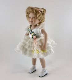 "1988 Shirley Temple Movie Classics By Danbury Mint - Shirley Temple \"Baby Take A Bow\" Porcelain Doll by Elke Hutchens This beautiful porcelain doll captures Shirley Temple in one of her most famous movie roles. She is hand painted and dressed in a masterful re-recreation of the original costume from \"Baby Take A Bow.\" The outfit is completed with her white lace socks and white leather shoes with tiny pearls as buttons. She is in beautiful condition and ready to display complete with stand. White Lace Socks, Temple Movie, Movie Classics, White Leather Shoes, Famous Movies, Lace Socks, Danbury Mint, Shirley Temple, Porcelain Doll