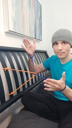 a man sitting on top of a bed holding his hands up in the air while wearing a beanie