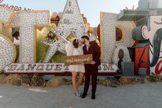 Celebrate love with a vibrant, retro vibe! This Neon Museum Wedding features a sweet kiss under eclectic vintage neon signs. The groom rocks a burgundy suit complementing the bride's chic short wedding dress paired with elegant wedding shoes. Perfect for unique wedding ideas, this setting is a visual treat for anyone dreaming of a whimsical celebration 🥂✨ #weddingideas #simpleweddingdress #proposalideas #bridalshowerthemes #weddingshoes Las Vegas Wedding Venue, Las Vegas Wedding Photography, Las Vegas Engagement, Museums In Las Vegas, Vegas Elopement, Las Vegas Elopement