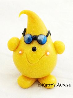 a yellow toy with sunglasses on it's head and eyes sitting in front of a white background