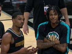 two young men standing next to each other on a basketball court with their arms crossed