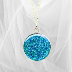 This beautiful circular glitter pendant necklace is crafted with precision using the finest quality resin and glitter, set in a 1-inch round stainless-steel setting, and finished with either a 20" silver-plated chain or a 20" black waxed necklace cord. Its vibrant green hue and sparkly finish will brighten up any outfit and make you stand out from the crowd. Ideal for special occasions.