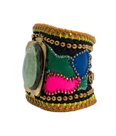 Introducing the **Sumersus Cuff** by De Petra, a stunning handmade piece inspired by Max Ernst's captivating painting, "Sumersus." This signature cuff is a vibrant fusion of color and craftsmanship, designed to make a bold and artful statement. The cuff is crafted from a luxurious mix of black Italian leather and striking neon accents in pink, green, and blue. This dynamic combination of colors creates a visually arresting base that is both modern and edgy. At the heart of the cuff lies a hand-forged brass centerpiece, featuring a mesmerizing green amethyst pendant. The pendant's serene green hues reflect the surreal and dreamlike quality of Ernst's "Sumersus," adding a touch of elegance and mystique to the piece. Intricate hand-embroidered brass elements weave through the design, adding t Handmade Multicolor Cuff Bracelet, Unique Handmade Multicolor Cuff Bracelet, Unique Multicolor Handmade Cuff Bracelet, Unique Multicolor Cuff Bracelet For Festival, Multicolor Handmade Cuff Bracelet Wearable Art, Multicolor Handmade Cuff Bracelet - Wearable Art, Handmade Multicolor Cuff Bracelet Wearable Art, Luxury Handmade Multicolor Bracelets, Luxury Handmade Multicolor Bracelet