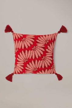 a red and pink pillow with tassels on it