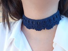 a woman wearing a blue crochet choker necklace on her left neck and white shirt