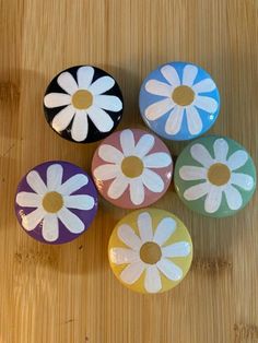 four painted flowers sitting on top of a wooden table