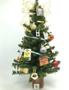 a small christmas tree decorated with ornaments and tags on the top, sitting in a pot