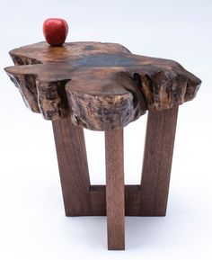 an apple sitting on top of a piece of wood that is shaped like a tree stump