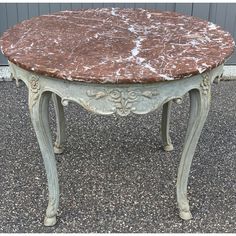 an old table with marble top sitting on the ground