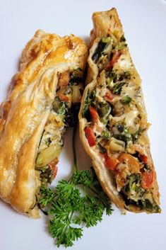 a white plate topped with two pieces of pie next to a green leafy garnish