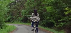 a person riding a bike down a road in the woods