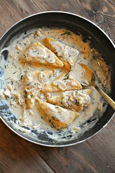 a pan filled with chicken and sauce on top of a wooden table