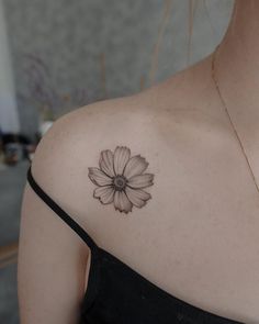 a woman's shoulder with a flower tattoo on the left side of her upper arm