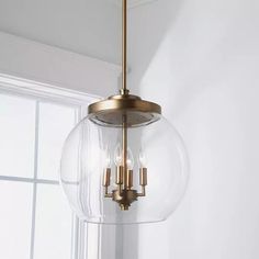 a light fixture hanging from the ceiling in a room with white walls and window behind it