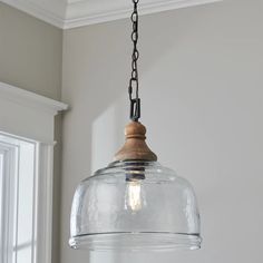 a glass light fixture hanging from a ceiling in a room with white walls and windows