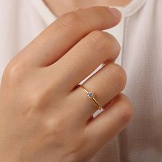 a woman's hand wearing a gold ring with a diamond set in the middle