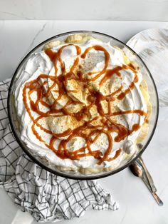 a dessert with whipped cream and caramel drizzled on top in a glass dish