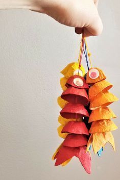 a person is holding up some colorful paper fish ornament hanging from a string