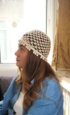 a woman wearing a crocheted hat sitting on a couch next to a window