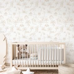 a teddy bear sitting in a crib next to a wall with palm trees on it