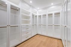 an empty walk in closet with lots of white cabinets and wood flooring on the walls