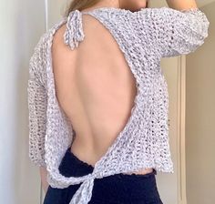 the back of a woman's sweater is shown with her hands on her head