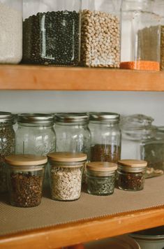 jars and containers filled with grains sit on a shelf in a pantry next to other food items